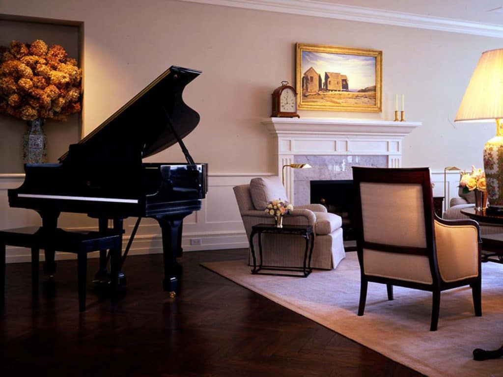 Baby grand piano in entertaining area with chairs and flowers