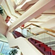 Ornate stairs to upper two floors with glass walls and gold trim.