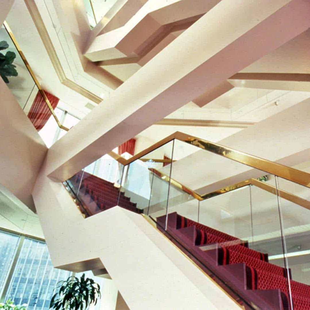 Ornate stairs to upper two floors with glass walls and gold trim.