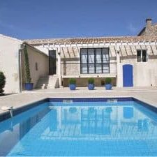 Back entrance of home with rectangular pool, steps, and four potted plants
